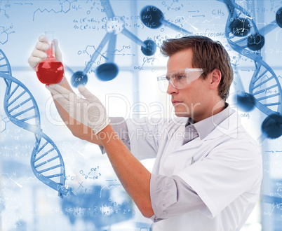 Scientist looking at beaker of red liquid