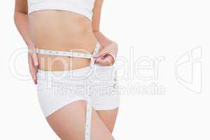 Fit woman measuring waist with measuring tape