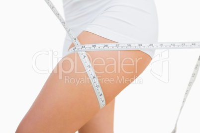 Midsection of fit woman measuring thigh