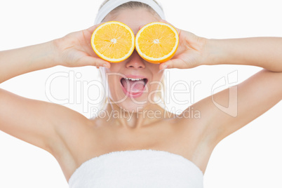 Surprised woman holding orange slices in front of eyes