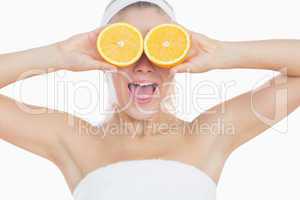 Surprised woman holding orange slices in front of eyes