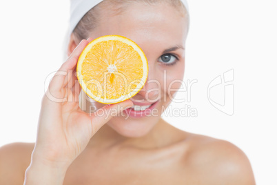 Happy woman holding orange slice over eye