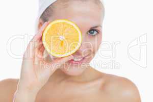 Happy woman holding orange slice over eye