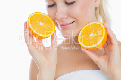 Woman with eyes closed holding slices of orange