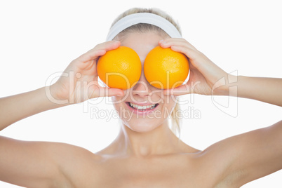 Happy woman holding oranges in front of eyes