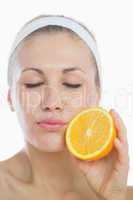 Young woman with eyes closed holding orange slice