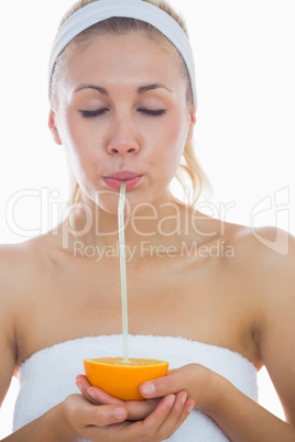 Woman sipping from an orange with straw