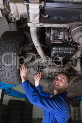 Happy mechanic under car