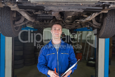 Mechanic with clipboard under car