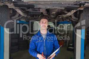 Mechanic with clipboard under car