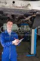 Repairman preparing checklist under car