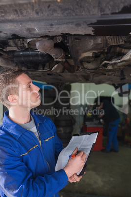 Mechanic with clipboard examining car