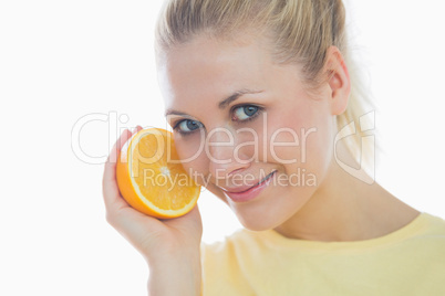 Happy young woman holding slice of orange