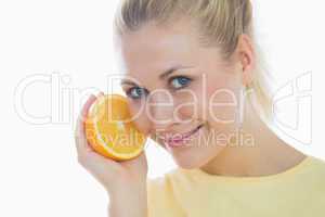 Happy young woman holding slice of orange