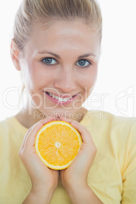 Happy woman showing slice of orange