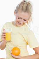 Woman holding orange and glass of juice