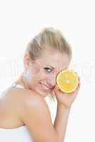 Woman holding slice of orange in front of eye
