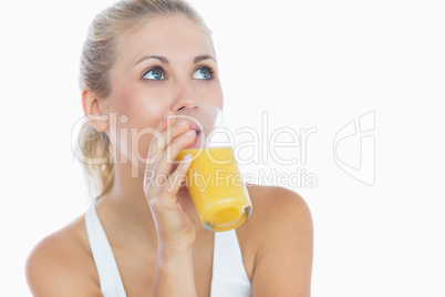 Woman drinking orange juice as she looks up