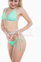 Woman in bikini measuring waist