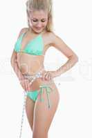 Fit woman in bikini measuring waist