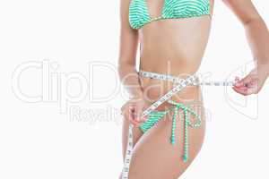 Woman in bikini measuring waist