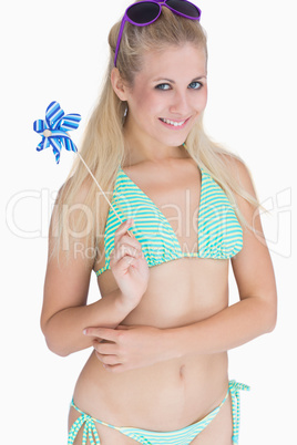 Happy woman in bikini holding pinwheel