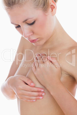 Naked woman examining breast