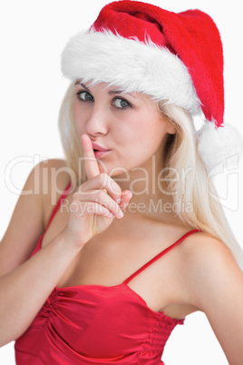 Woman in santa hat making silence gesture