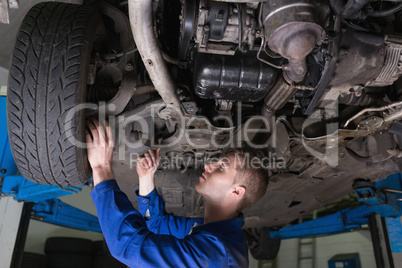 Mechanic under car in garage