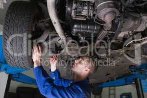 Mechanic under car in garage
