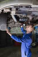 Male mechanic examining car