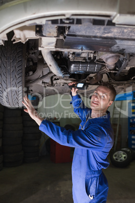 Male car mechanic examining vehicle
