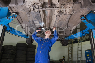 Mechanic inspecting car using flashlight