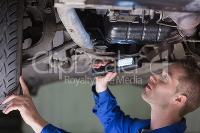 Young mechanic examining car