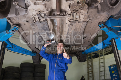 Repairman under car gesturing thumbs up