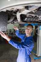 Confident mechanic repairing car