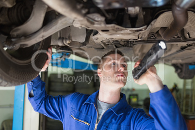 Mechanic with frashligth examining car