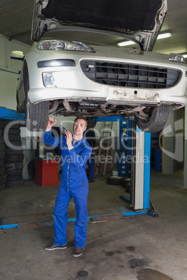 Mechanic working under raised car in workshop