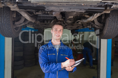 Mechanic preparing checklist under car
