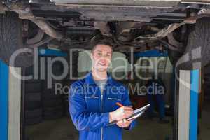 Mechanic preparing checklist under car