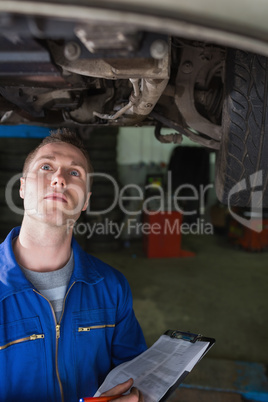 Mechanic with clipboard examining car