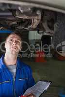 Mechanic with clipboard examining car