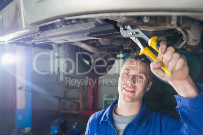 Happy mechanic repairing car with pliers