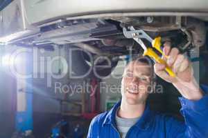 Happy mechanic repairing car with pliers
