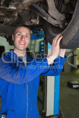 Happy mechanic examining car tire