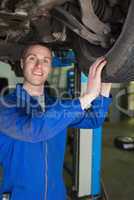 Happy mechanic examining car tire