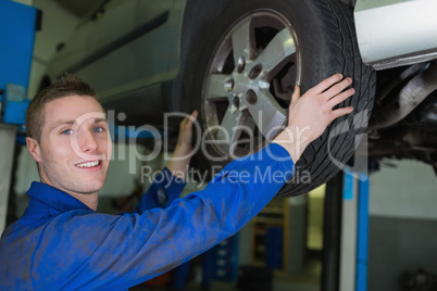 Male mechanic working on wheel of car