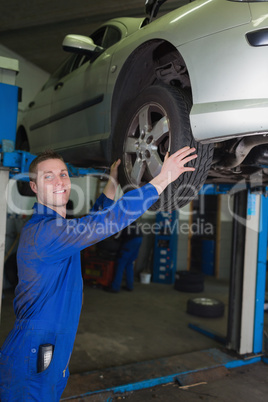 Car on hydraulic lift as mechanic examining tire