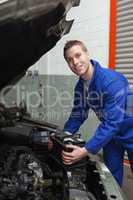 Happy mechanic with battery by car