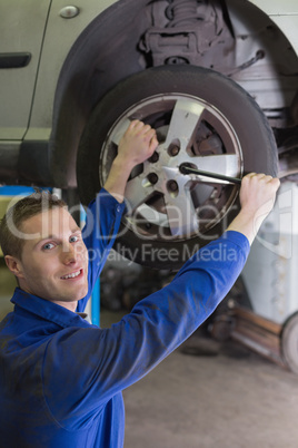 Male mechanic fixing car tire with wrench